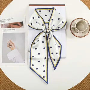 Detail van een witte zijden haarband met blauwe stippen en gele rand op een tafel