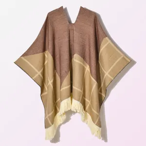 Detail of vintage knit poncho featuring brown patchwork, plaid patterns and fringe tassel hem