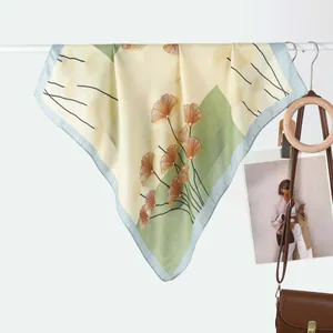 Detail of silk square scarf featuring elegant ginkgo leaf pattern and sheer fabric texture