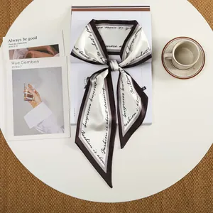 Detail van zijden satijnen sjaal met elegante zwarte cursieve tekst en koffie contrastrand
