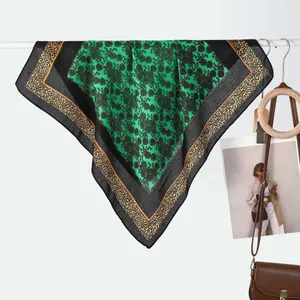 Detailed close-up of a leopard print silk scarf with floral pattern and green center