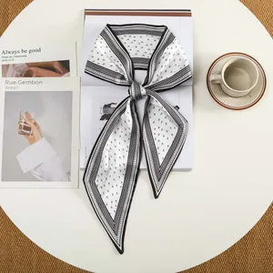 Detailopname van een zwart-witte zijden sjaal met geometrisch patroon gestrikt op een tafel
