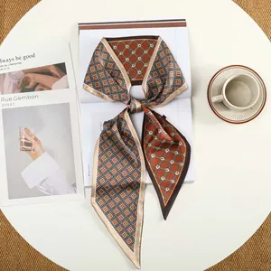 Detail van geometrische zijden sjaal in oranje en bruin op een minimalistische tafel