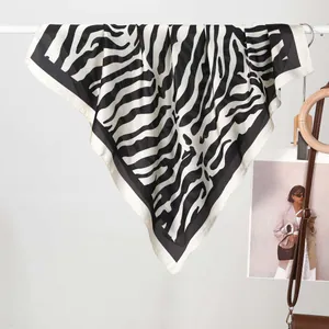 Dettaglio di un foulard in raso con motivo zebrato appeso a un supporto in stile moderno