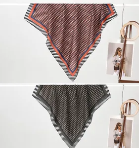 Detail von Seidenschals mit geometrischem Druck in Orange-Blau und Braun-Grün