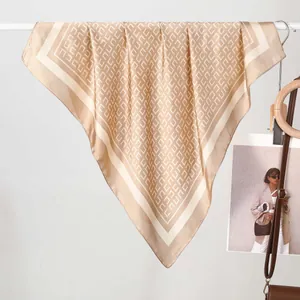 Élégant foulard en soie champagne avec motifs géométriques suspendu sur support