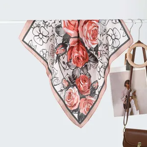 Detail of floral silk scarf with red roses and elegant pink border on a display hanger