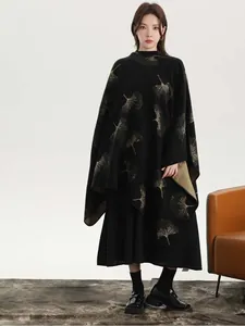Detail of elegant black knit shawl with golden ginkgo leaf patterns and draped texture