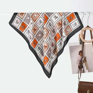 Detail of silk square scarf featuring equestrian horse prints and elegant orange patterns