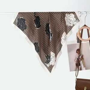 Detail of silk scarf with houndstooth and floral print on white hanger with accessories