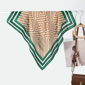 Detailed view of emerald and bronze geometric silk scarf on a stylish display