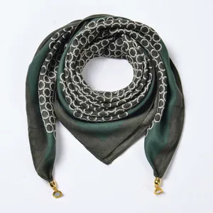 Detail view of dark green striped velvet scarf with white geometric rings and gold pendants