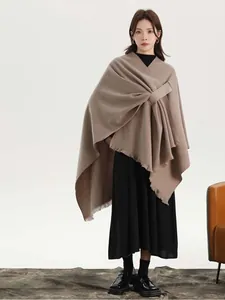 Detail of soft beige cashmere shawl with side buckle closure and fringe hem texture