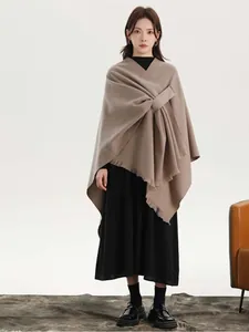 Detail of camel wool poncho featuring a side-tie closure and delicate fringe trimming