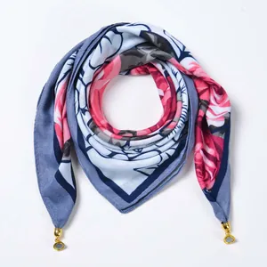 Detail view of floral print scarf with blue rose patterns and gold metal pendant charms