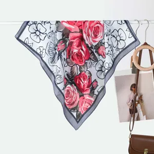 Detail of silk scarf with red rose pattern hanging on a bar with lifestyle props