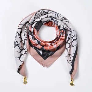 Detail of floral silk scarf with golden metal pendants and orange-pink borders