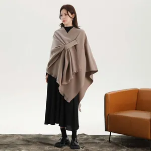 Thick khaki wool poncho cape with side ties and fringe detail on black knit dress
