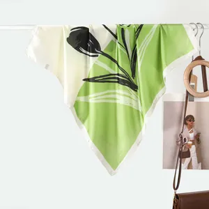 Green and beige silk scarf with abstract tulip print hanging on a white rack display
