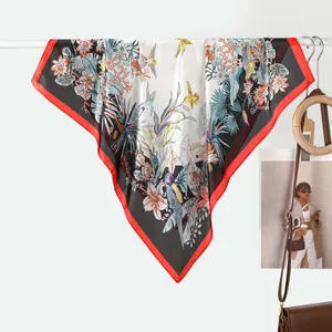 Close-up of a floral silk scarf with tropical bird prints and a bold red border edge