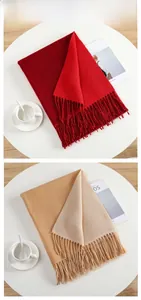 Close-up of soft cashmere-feel scarves in red and oatmeal with fringe detail