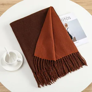 Detail of soft cashmere-like scarf with dual-tone brown and orange weave and tassels