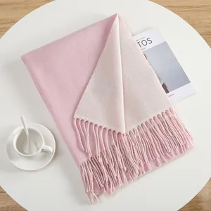 Pink and beige cashmere-style pashmina shawl with tassels on a minimalist white table