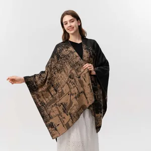 Full view of women's knitted poncho shawl with brown and black abstract jacquard pattern