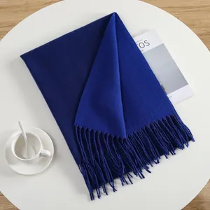 Detail of royal blue scarf with fringe on white table with coffee and magazine