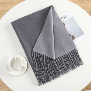 Detailed view of grey cashmere-feel knit scarf featuring fringe ends and dual-tone design
