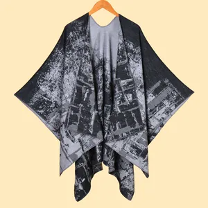 Detail of knitted women's poncho shawl featuring black and grey abstract jacquard texture