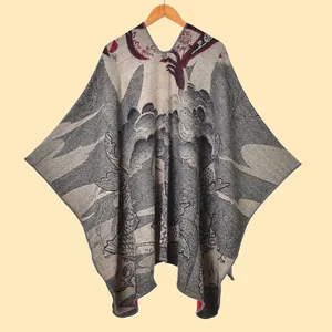 Macro-opname van gebreide poncho met V-hals, vintage koimotieven en franjes aan rand