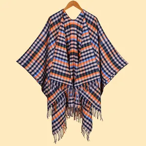 Détail de la texture à carreaux et des franges du poncho bleu marine et orange