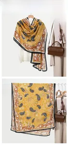 Detail of ginger yellow linen scarf with black paisley and scroll patterns for women