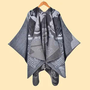 Detailopname van grijze jacquard gebreide sjaal met artistieke patronen en afgewerkte zoom