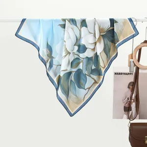 Detail of light blue silk scarf featuring realistic white magnolia floral patterns and gold edges