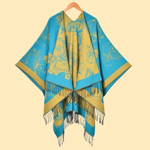 Detail of vintage floral pattern and black tassels on blue yellow winter poncho