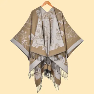 Detailed view of the khaki knitted shawl featuring large white floral jacquard and black tassels