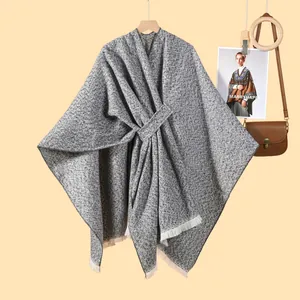 Detail eines grauen Ponchos mit Taillenband und weißen Fransen am Saum für Damen