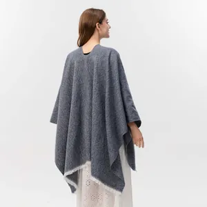 Detaillierte Rückansicht des dunkelblauen Strickponchos mit Fransen und Textur