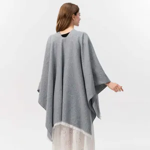 Detail eines grauen Strickschals mit Fransensaum und Bindegliedern am Modell getragen