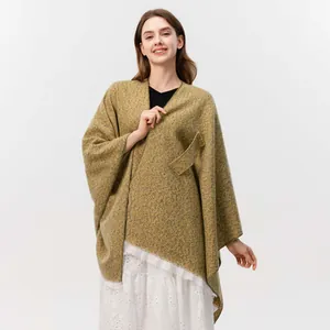 Detailansicht des senfgelben Strick-Ponchos mit Fransensaum und einer Taschen-Applikation