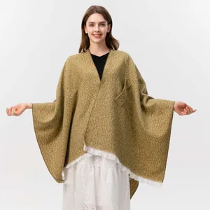 Detail eines senfgelben Strickponchos mit Fransenbesatz und schräger Taschenstruktur