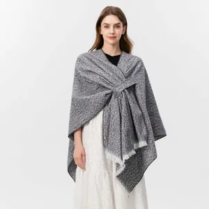 Detail des grau melierten Strickschals mit feinen Fransen und gekreuztem Wickel-Design