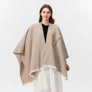 Detailansicht des beigen Strickponchos mit feinen Fransen und praktischer Seitentasche