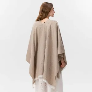 Detail eines Damen-Strickponchos mit Fransen am Saum und beige meliertem Webmuster