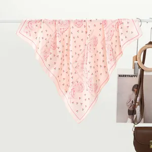 Pink paisley silk scarf with cherry print hanging elegantly on a white metal rack