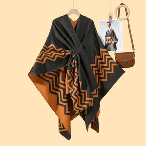 Close-up of thick knitted poncho featuring grey and orange geometric wave patterns