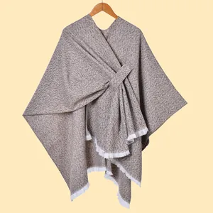 Detail der Tweed-Poncho-Textur mit braun gesprenkeltem Stoff und weißen Quastenfransen