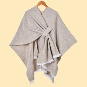Detailansicht eines beigen Strickschals mit feinen weißen Fransen und Riemenverschluss